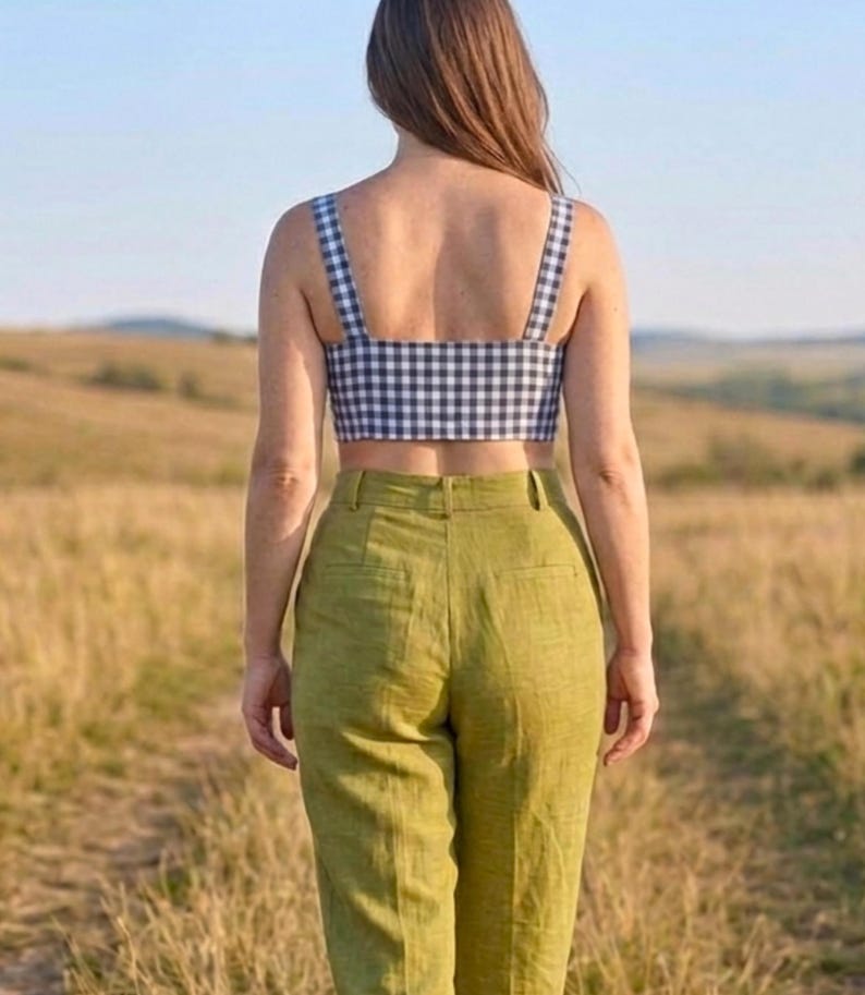 May include: A cropped top featuring a black and white gingham check pattern with wide shoulder straps, paired with high-waisted olive green trousers that have a structured waistband, belt loops, and two visible back pockets.