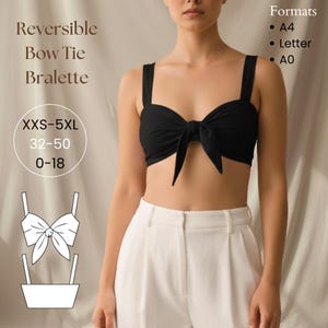 以下が含まれることがあります： 黒のリバーシブルボウタイブラレット。太いストラップと中央の蝶ネクタイが特徴です。ブラレットは白いパンツと組み合わせています。画像には「Reversible Bow Tie Bralette」と「XXS-5XL、32-50、0-18」と書かれています。