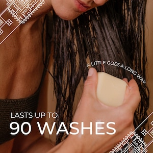 May include: A rectangular off-white solid shampoo bar being applied to wet dark hair. The text on the image reads A LITTLE GOES A LONG WAY and LASTS UP TO 90 WASHES. The bar is held in a hand, showing its smooth, solid, and light-colored surface.