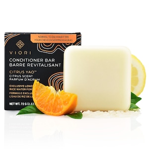 May include: A white conditioner bar with the text "VIORI Conditioner Bar Barre Revitalisant Citrus Yao™ Citrus Scent Parfum d'Agrum Exclusive Longs Rice Water For Formule Exclu L'Eau de Riz de Lo Net Wt. 72 g (2.53)" on a black background. The bar is surrounded by a slice of orange, a lemon, and rice.