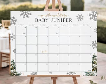 May include: A white calendar sign on a wooden easel with the text "guess the arrival date for BABY JUNIPER". The calendar has a grid layout with dates and is decorated with snowflakes and evergreen trees. The sign is displayed outdoors.