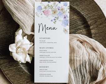 Könnte beinhalten: Eine weiße Speisekarte mit einem floralen Design und dem Wort "Menu" in schwarzer Schrift. Die Speisekarte listet Vorspeisen, Hauptgerichte und Desserts auf. Die Speisekartenartikel umfassen Feigensalat, Pesto-Pasta, gebratene Jakobsmuscheln, Kräuter-Brathähnchen, Vanillekuchen und Schokoladenkekse.