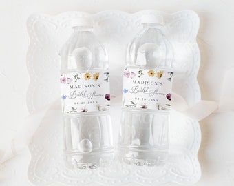 May include: Two clear plastic water bottles with floral patterned labels that say "Madison's Bridal Shower 08.20.20XX". The bottles are on a white lace doily.