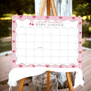 May include: A pink and white calendar on a wooden easel, designed for a baby shower. The calendar is decorated with bows and the text "guess the arrival date for BABY JUNIPER". The calendar includes dates for April, May, and June.