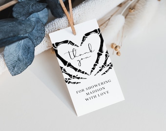 May include: A white thank you tag with a black skeleton hand design forming a heart shape. The text "thank you" is inside the heart. The text "For showering Madison with love" is below the heart.