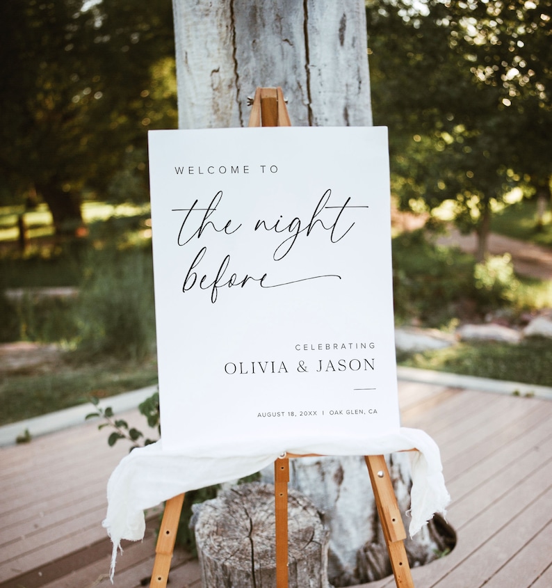 K&ouml;nnte beinhalten: Ein wei&szlig;es Schild mit schwarzem Text, das "Willkommen zur Nacht davor" ank&uuml;ndigt und Olivia & Jason am 18. August 20XX in Oak Glen, CA, feiert. Das Schild steht auf einem Staffelei.