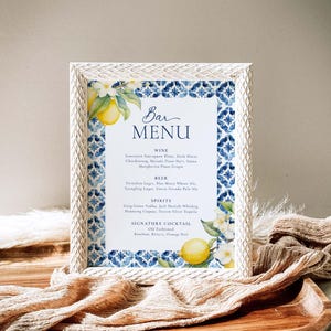 May include: A white framed bar menu with a blue and white tiled pattern and lemons and flowers. The menu lists wine, beer, spirits, and a signature cocktail: Old Fashioned.