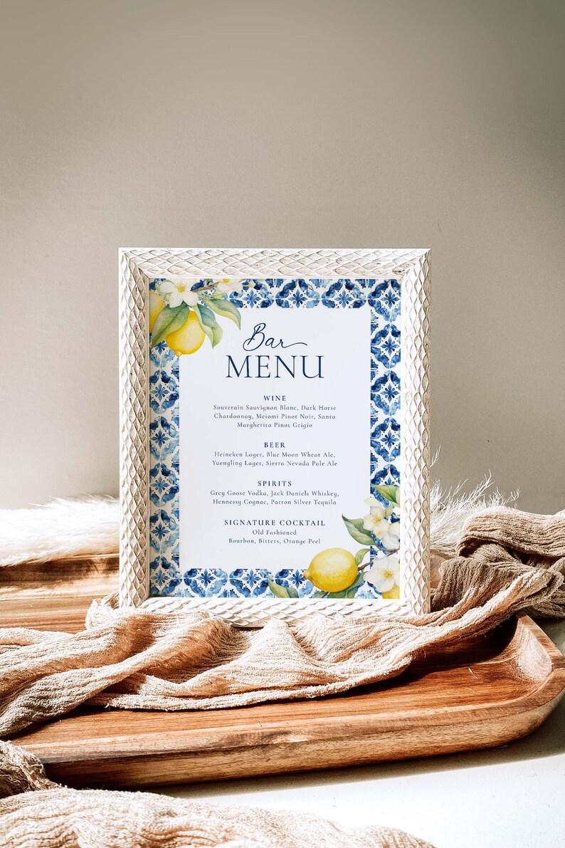 May include: A white framed bar menu with a blue and white tiled pattern and lemons and flowers. The menu lists wine, beer, spirits, and a signature cocktail: Old Fashioned.