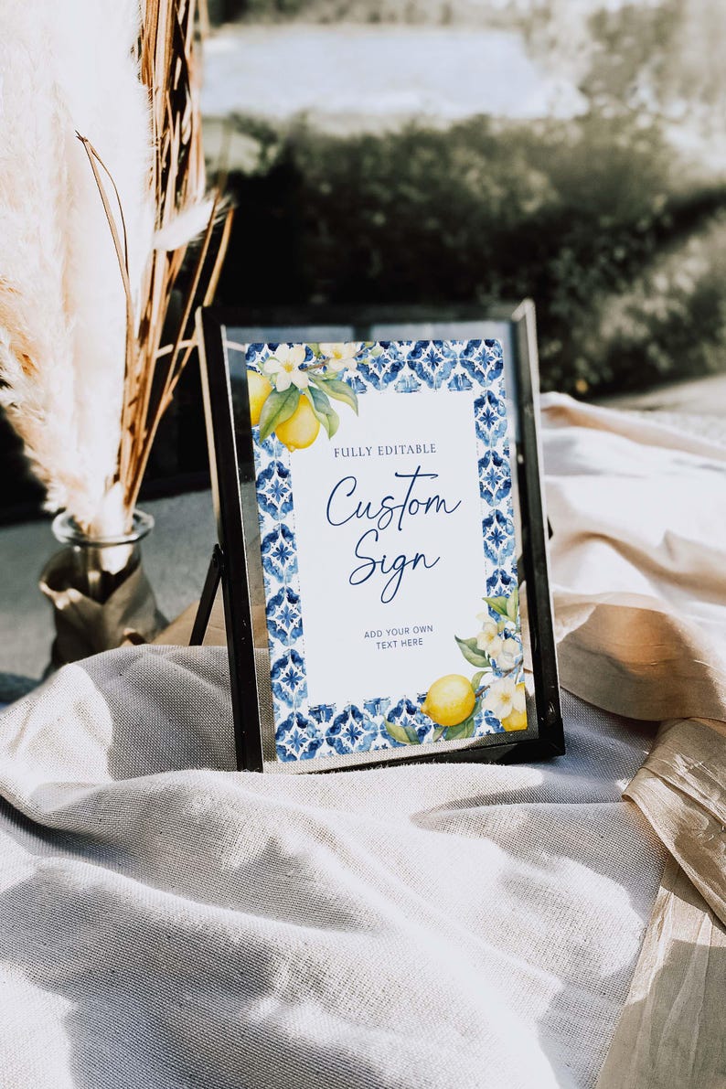 May include: A printable sign with a blue and white tile pattern border and a lemon and flower illustration. The sign says "Fully Editable Custom Sign Add Your Own Text Here".