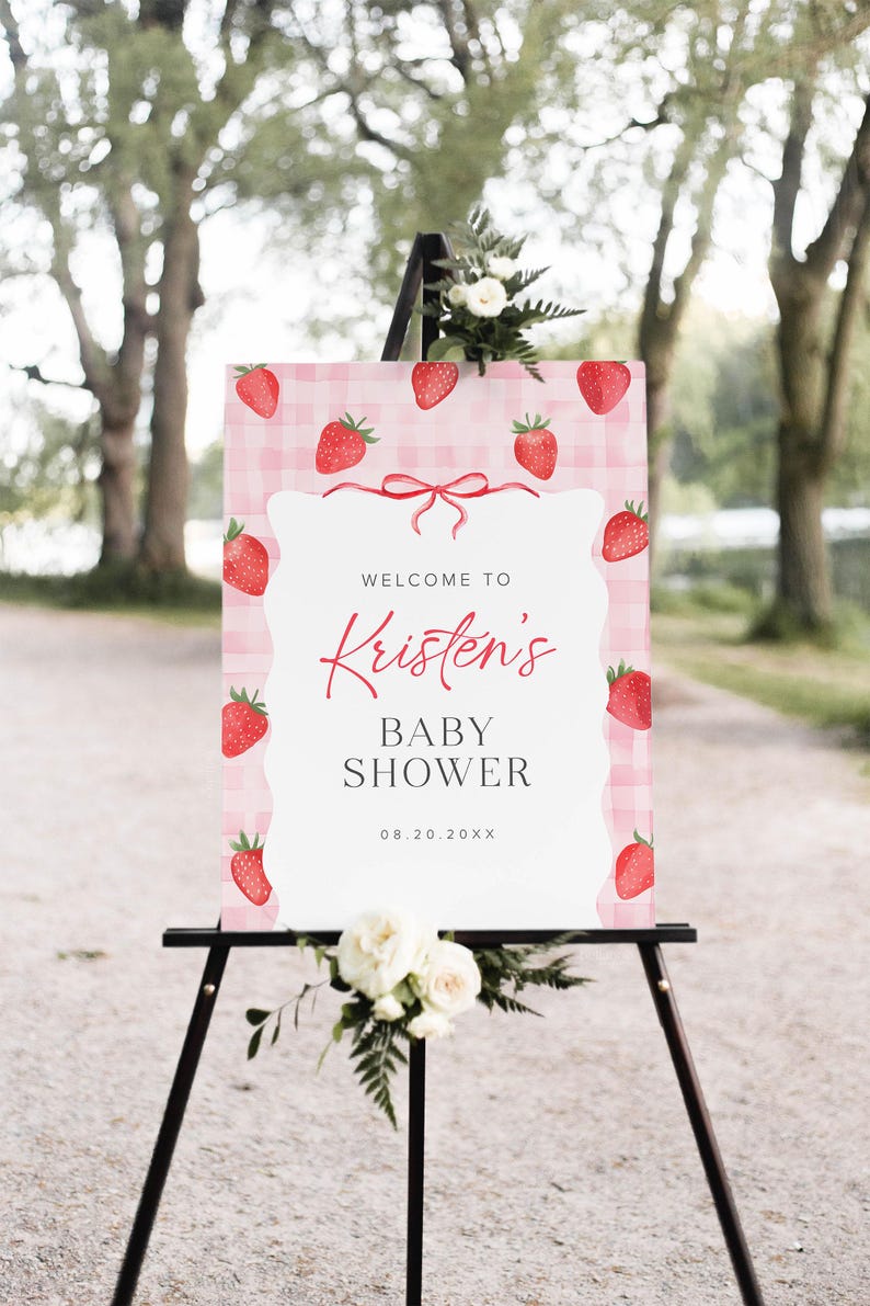 May include: A pink and white gingham baby shower welcome sign with red strawberries and a red ribbon. The sign reads "Welcome to Kristen's Baby Shower 08.20.20XX".