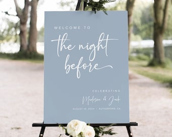May include: A light blue welcome sign with white text that reads "Welcome to the night before celebrating Madison & Jack August 18, 20XX Rutherford, CA". The sign is on a black easel.