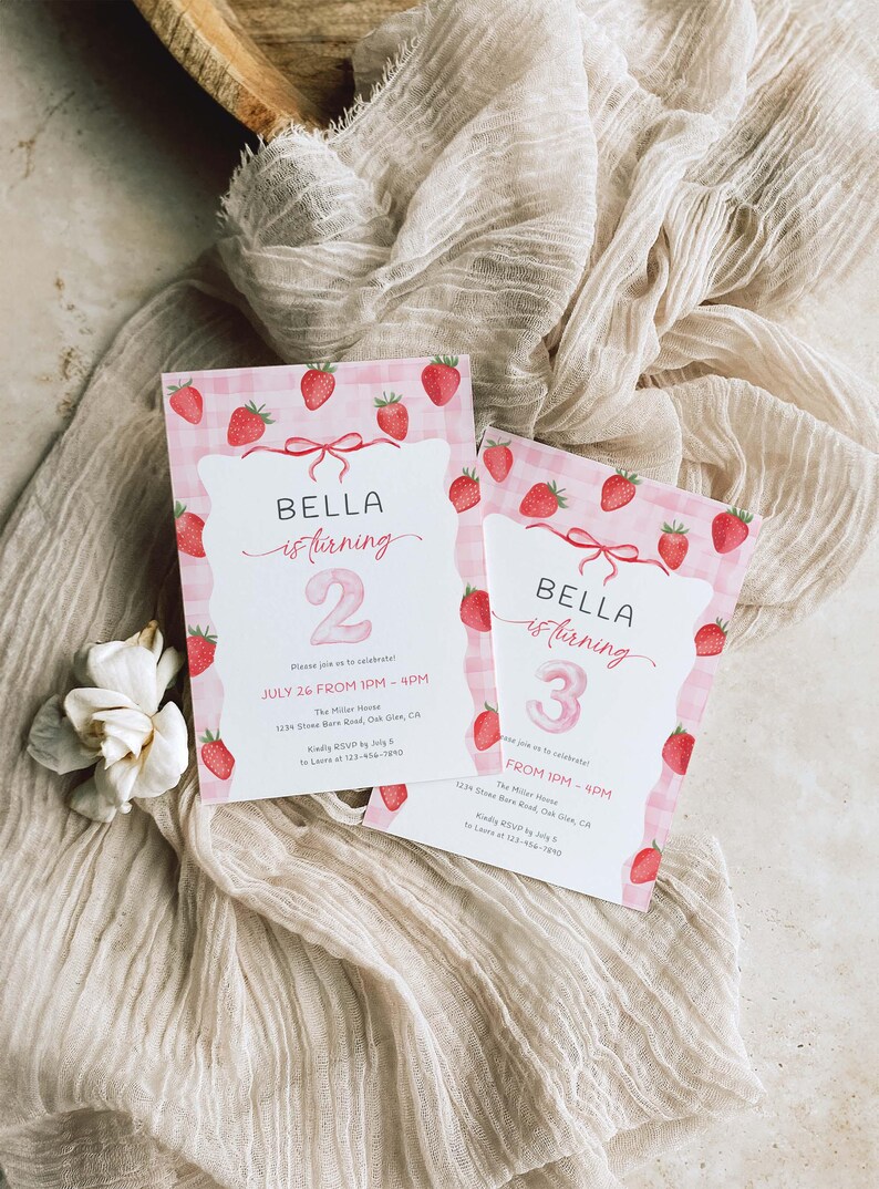 Może przedstawiać: Dwa r&oacute;żowe zaproszenia urodzinowe z truskawkami i kokardkami. Zaproszenia głoszą "BELLA is turning 2" i "BELLA is turning 3". Leżą na beżowym tle z tkaniny.