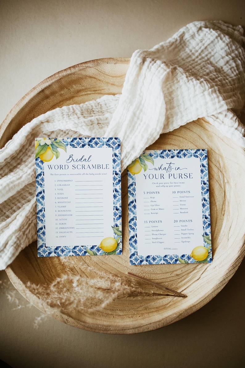 May include: Two printable bridal shower game cards with a blue and white tile pattern and lemons. The first card is a word scramble game with the title "Bridal Word Scramble". The second card is a "What's in Your Purse" game with a list of items and points.