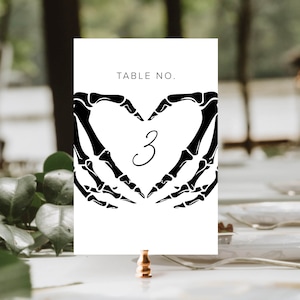 May include: White card with black skeleton hands forming a heart shape with the number 3 inside. The card reads "TABLE NO."
