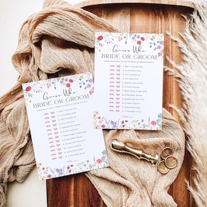 May include: Two floral-themed "Guess Who Bride or Groom" game cards with a list of 12 questions to determine who is more likely to do each action. The cards are on a wooden surface with a gold wax seal.