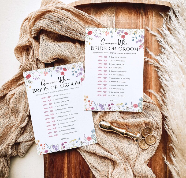 May include: Two floral-themed "Guess Who Bride or Groom" game cards with a list of 12 questions to determine who is more likely to do each action. The cards are on a wooden surface with a gold wax seal.