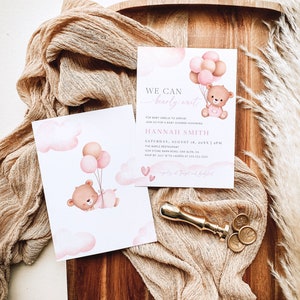 Pode incluir: Um convite de ch&aacute; de beb&ecirc; rosa e branco com uma ilustra&ccedil;&atilde;o em aquarela de um urso marrom segurando bal&otilde;es rosa e bege. O texto diz "We can barely wait" para a beb&ecirc; Amelia. O convite inclui a data, a hora e o local do evento.