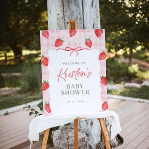 May include: A pink and white gingham welcome sign with red strawberries and the text "Welcome to Kristen's Baby Shower 08.20.20XX".