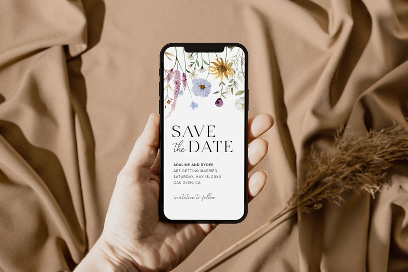 May include: A mobile phone screen displaying a save the date card with a floral design. The text reads "Save the Date", "Adaline and Ryder are getting married", "Saturday, May 18, 20XX", "Oak Glen, CA", and "Invitation to follow".
