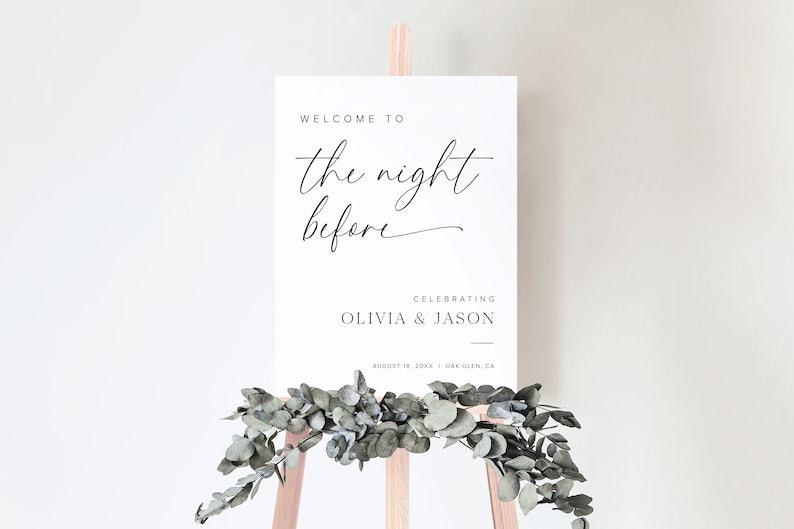 K&ouml;nnte beinhalten: Ein wei&szlig;es Schild mit schwarzem Text, auf dem steht "Willkommen zur Nacht vor der Feier von Olivia & Jason am 18. August 20XX in Oak Glen, Kalifornien". Das Schild steht auf einem Holzst&auml;nder mit Gr&uuml;npflanzen.