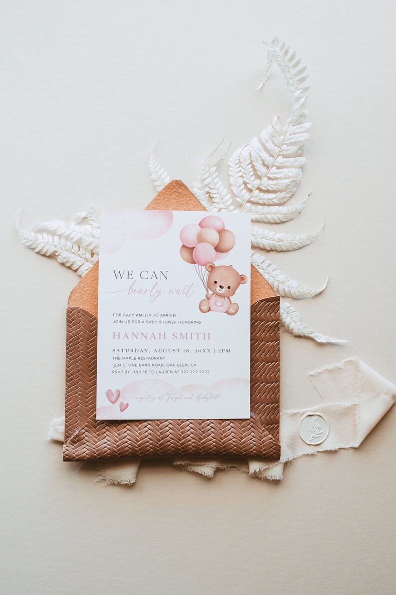 Pode incluir: Um convite de ch&aacute; de beb&ecirc; rosa e marrom com um fundo de aquarela. O convite apresenta um urso de pel&uacute;cia segurando bal&otilde;es e o texto "We can barely wait" para a beb&ecirc; Amelia. O convite inclui a data, a hora e o local do ch&aacute; de beb&ecirc;.