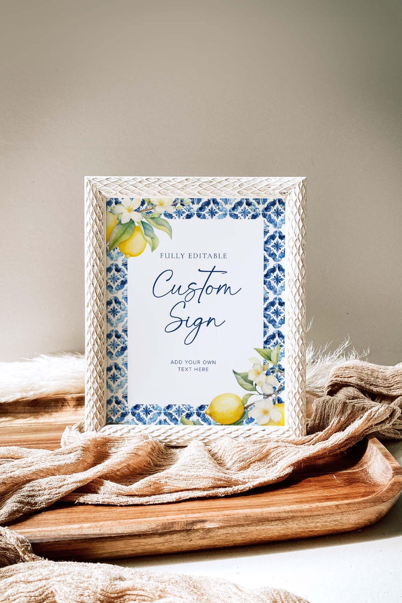 May include: A white frame with a blue and white tiled border surrounds a printable sign that says "Fully Editable Custom Sign Add Your Own Text Here". The sign features a watercolor illustration of lemons and white flowers.