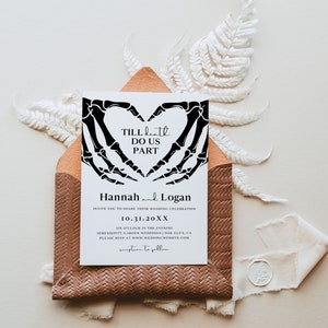 Puede incluir: Una invitaci&oacute;n de boda blanca con manos de esqueleto negras formando una forma de coraz&oacute;n. El texto dice "Till Death Do Us Part" e incluye los nombres Hannah y Logan, la fecha 10.31.20XX y la ubicaci&oacute;n Serendipity Garden Weddings | Oak Glen, CA.
