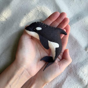Felt orca plush toy in hand, small handmade whale, soft ocean animal toy