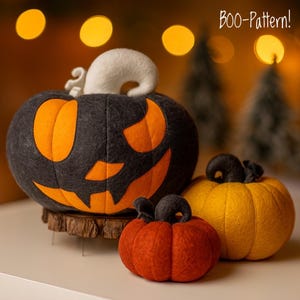 May include: Three felt pumpkins in varying sizes and colors. The largest is black with orange cutouts, a white ghost, and a carved face. The other two are orange and yellow. The text "BOO-Pattern!" is in the upper right corner.
