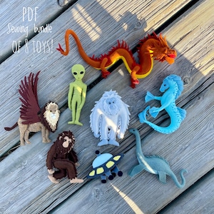 Può includere: Una collezione di otto figure di giocattoli in feltro, tra cui un drago, un alieno, uno yeti, un cavalluccio marino, un grifone, un bigfoot, un UFO e un dinosauro. I giocattoli sono in vari colori, come arancione, verde, blu e marrone. Il testo "PDF Sewing bundle OF 8 TOYS!" è in alto.