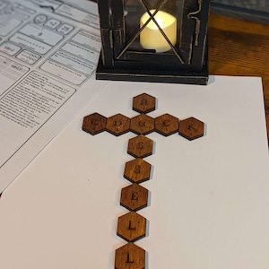 May include: A wooden cross made of hexagonal tiles with the letters "RUCKSACK" spelled out across the top and "SELL" spelled out down the center.