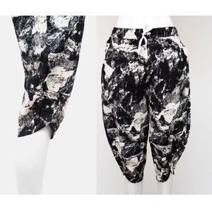May include: Black and white printed pants with a drawstring waist. The print features a mountain landscape design.