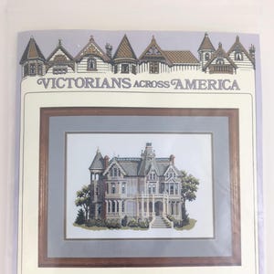 May include: A cross-stitch kit featuring the Charles Holbrook Mansion in San Francisco. The kit includes a detailed image of the Victorian house, with the text "VICTORIANS ACROSS AMERICA" at the top. The kit is designed by Debbie Patrick.