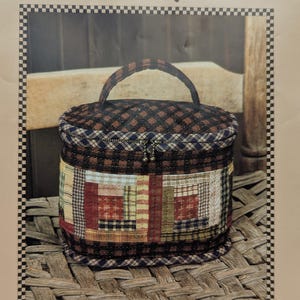 May include: A quilted, cylindrical bag with a handle, featuring a patchwork design around the middle and a checkered pattern on the top and bottom. The bag has a zipper closure and the text "Kimie's Quilts" at the top.