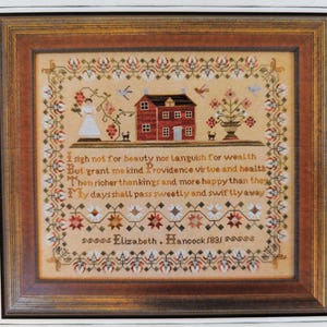 May include: Framed cross-stitch sampler in a brown wooden frame. The sampler depicts a red house, a woman, and floral and bird designs. Text includes "Elizabeth Hancock 1831". The background is beige.