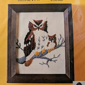 May include: A crewel embroidery kit titled Screech Owl by Erica Wilson featuring a stamped design on linen fabric. The image shows two owls in brown, white, and black perched on a blue branch. The kit includes yarn and a needle for a 4" x 5" project.
