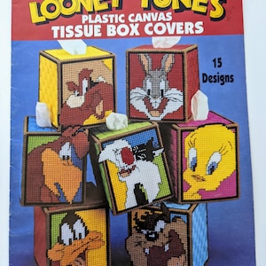 Puede incluir: Un folleto de fundas de cajas de pañuelos de lona de plástico de Looney Tunes. El folleto presenta imágenes de cajas de pañuelos terminadas con varios personajes de Looney Tunes, incluidos Bugs Bunny, el Pato Lucas y Piolín. El título es "Looney Tunes Plastic Canvas Tissue Box Covers."