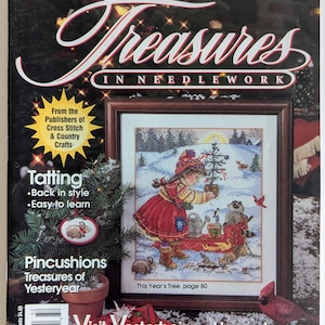 Op de afbeelding: Een magazinecover voor "Treasures in Needlework" van Better Homes and Gardens. De cover toont een ingelijste kruissteeksc&egrave;ne van een kind dat een kerstboom versiert in een besneeuwd landschap. Extra tekst bevat "Tatting" en "Pincushions".