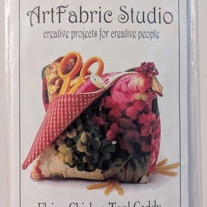May include: ArtFabric Studio Flying Chicken Tool Caddy & Pin Cushion Kit in a clear plastic bag. The package features a graphic of a fabric chicken with red checkered wings, floral patterns, yellow feet, and orange scissors tucked inside.