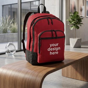 以下が含まれることがあります： 黒いトリムと黒いベースの赤いバックパックが木製のベンチの上に置かれています。 バックパックには複数のジッパー付きコンパートメントがあり、フロントポケットには白い文字で「your design here」と書かれています。 黒いショルダーストラップと上部のハンドルが付いています。