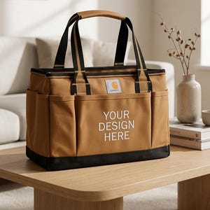 May include: A brown tote bag with black accents, featuring a top handle and shoulder straps. The bag has side pockets and the text "YOUR DESIGN HERE" in white. A small logo is visible on the front.