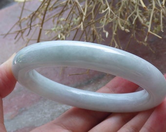 May include: A light green jade bangle bracelet. The bracelet is smooth and polished.