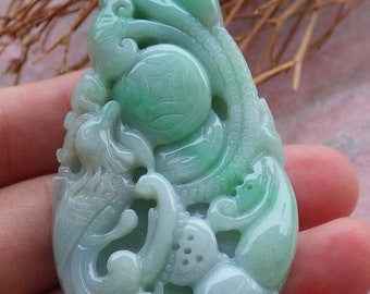 May include: A jade pendant carved with intricate details, featuring a green and white color scheme. The pendant depicts a dragon and other mythical creatures.