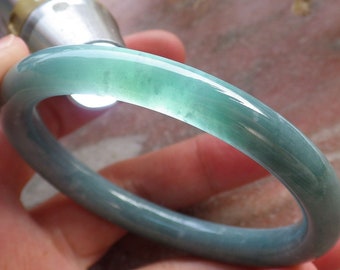 May include: A jade green bangle bracelet with a smooth, polished finish.