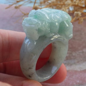 May include: A jade green ring with a carved dragon design. The ring is made of jade and has a polished finish.