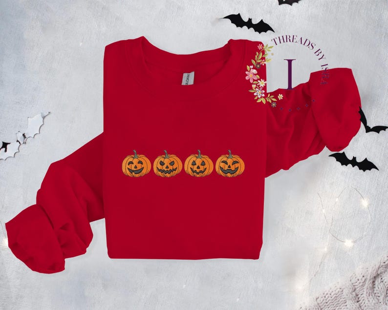 Pu&ograve; includere: Maglietta rossa a maniche lunghe con una fila di quattro zucche di Halloween arancioni ricamate. La maglietta ha un collo rotondo e maniche lunghe.
