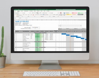 Puede incluir: Un ordenador de sobremesa muestra una hoja de cálculo de gestión de proyectos con un diagrama de Gantt. La pantalla muestra un plan de proyecto detallado con duraciones de tareas, dependencias e indicadores de progreso. También se ven un teclado, un cactus en maceta y una pila de libros.