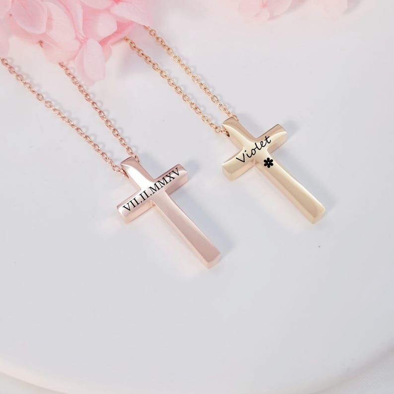 May include: Two gold cross necklaces. One cross is engraved with the Roman numeral date "VII.II.MMXV". The other cross is engraved with the name "Violet".
