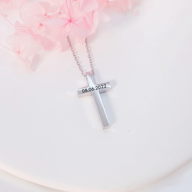 May include: Silver cross necklace with a chain and the date 08.06.2022 engraved on the front.