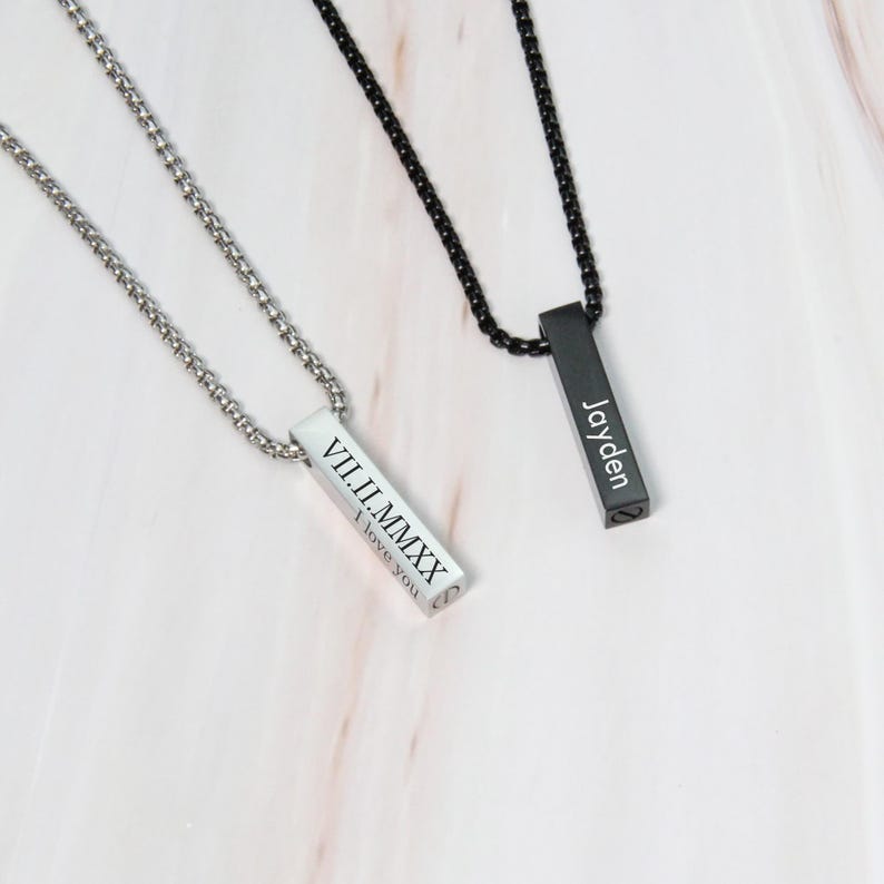 May include: Two silver bar necklaces with engraved text. One necklace has the Roman numeral date "VIII.II.MMXX" and the words "I love you". The other necklace has the name "Jayden" engraved on it.